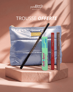 Trousse de maquillage argentée puroBIO offerte contenant un mascara vert, un crayon noir pour les yeux et deux crayons longue tenue pour les lèvres et le teint, posée sur un socle beige avec fond rose.
