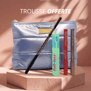 Trousse de maquillage argentée puroBIO offerte contenant un mascara vert, un crayon noir pour les yeux et deux crayons longue tenue pour les lèvres et le teint, posée sur un socle beige avec fond rose.